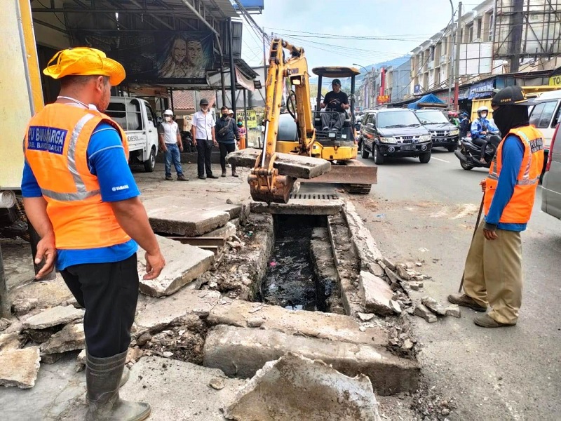 BERSIHKAN: Petugas Dinas PUPR mengerahkan alat berat untuk membersihkan saluran drainase di kawasan Pasar Panorama Lembang.DOK. PORKOPIM SETDA KBB